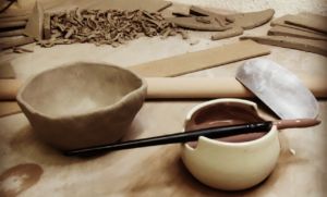 Proceso de creación de una pieza de cerámica en el taller ClayCats con herramientas y arcilla.