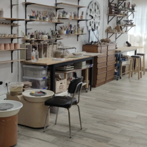 Espacio de trabajo en el taller de cerámica ClayCats con tornos, herramientas y materiales organizados en estanterías.