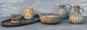 Set de cerámica artesanal con jarras, cuencos, tazas y bandeja esmaltados en tonos naturales.