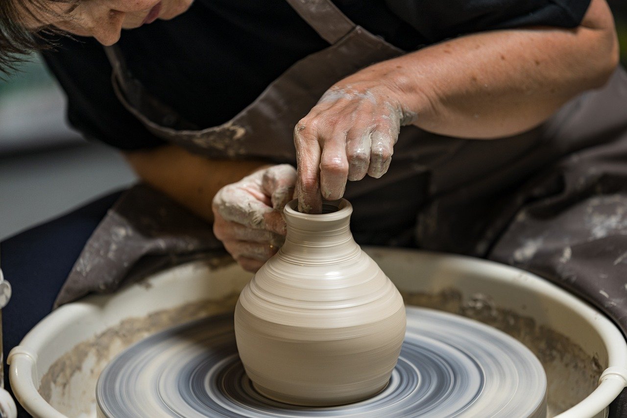 Manos moldeando un jarrón de cerámica en un torno durante un taller avanzado en ClayCats.